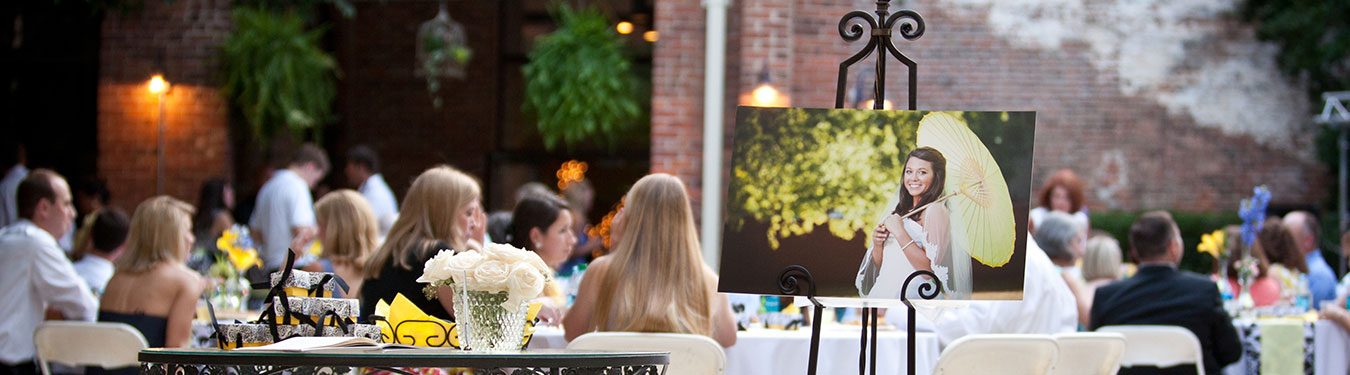 Multiple people sitting at a wedding reception with a photo of the bride on display